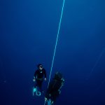 A freediver coming back from the depth with his safety diver. Dahab